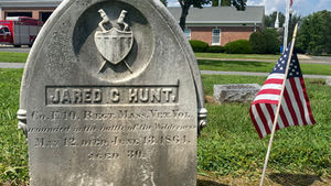 Marble gravestone of Jared C. Hunt with a shield and crossed bayonets