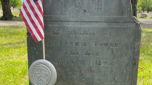 Slate gravestone with an urn and willow at the top and marked with a US flag