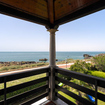 Balcony overlooking the sea with wooden railing and the blissful seafront.