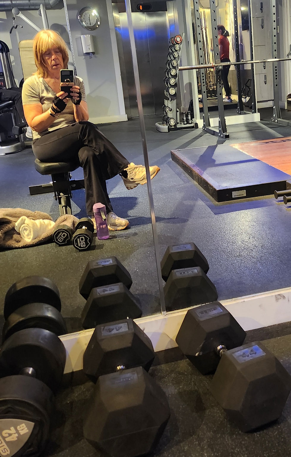 Photo of Cherie sitting in the gym with a water bottle and some weights