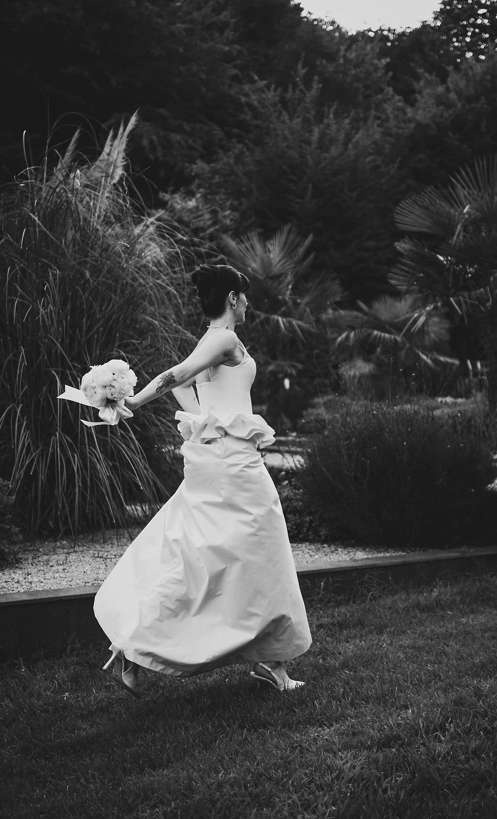 Bride in flowing gown running through a garden in Italy, natural and joyful destination wedding moment