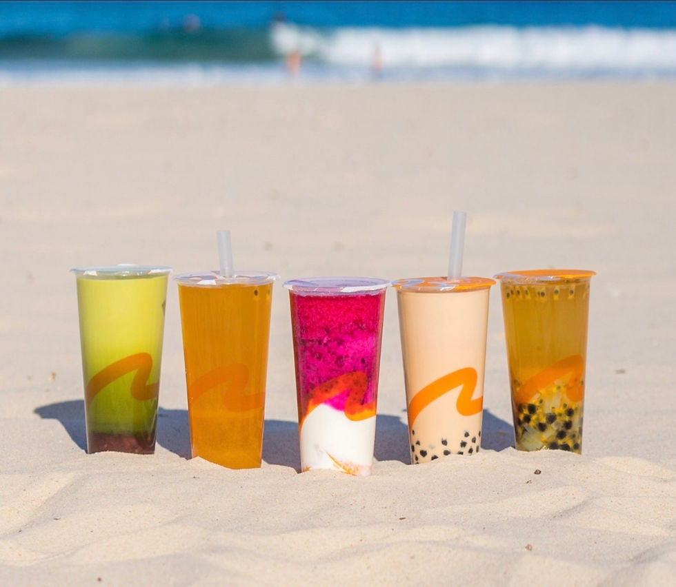 Five colorful drinks on a sandy beach with ocean