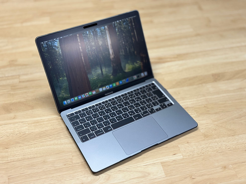 木製のデスクの上に置かれた、開いたMacBook Air。画面には森の風景の壁紙が表示されている。