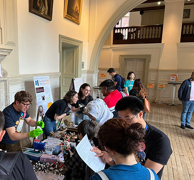 A group of researchers stand behind a table speaking to visitors about different archaeological methods.
