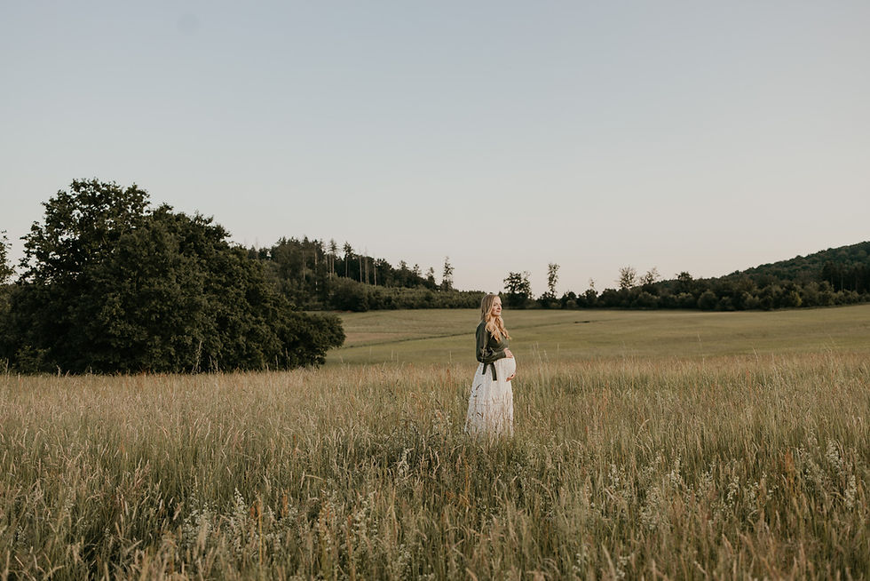 Werdende Mama steht auf einer Wiese