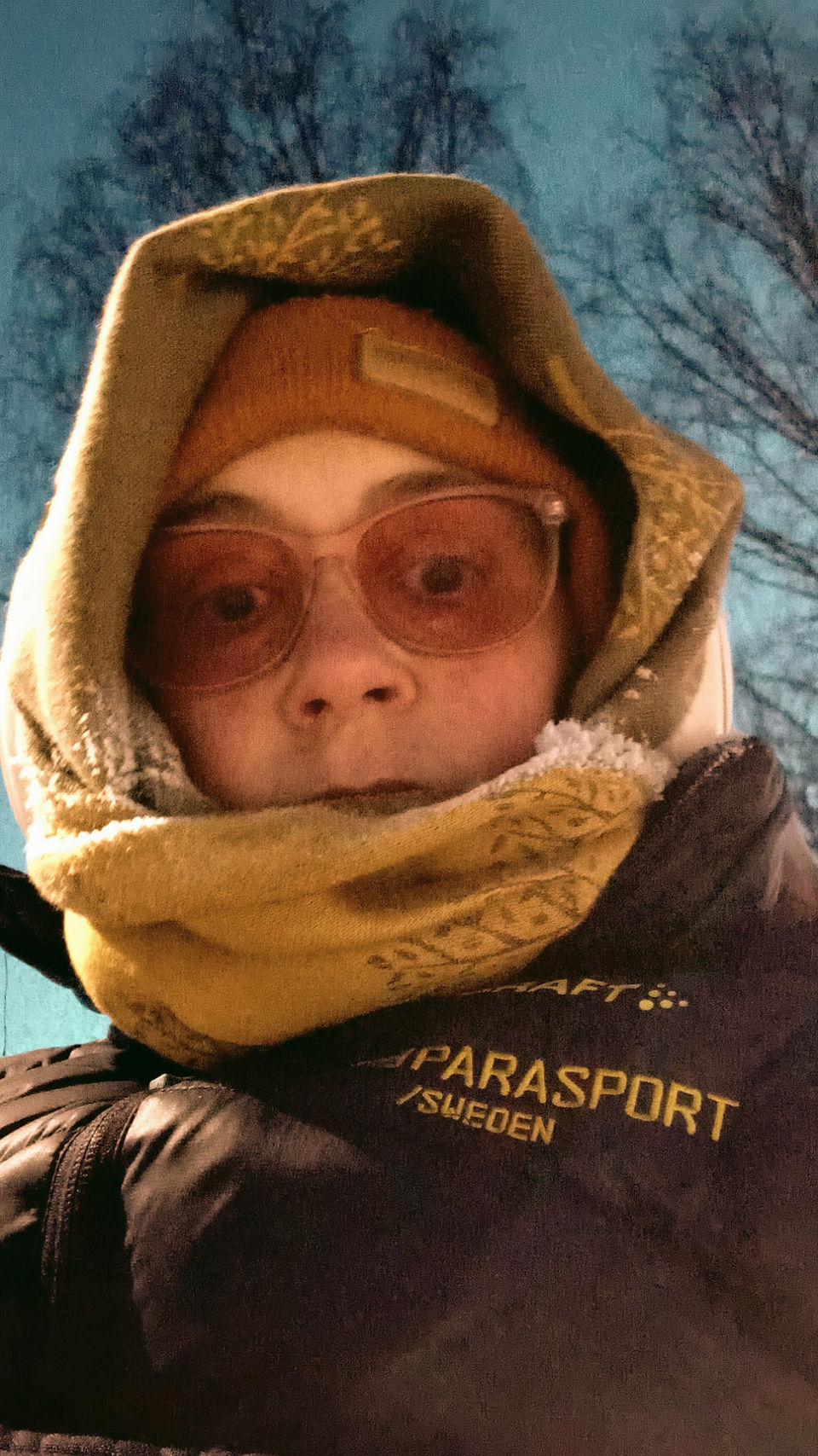 En selfie av jag, en vit kvinna. Ute med gul halsduk runt huvud, blå vinter jacka och glassögon som är rosa. Synligt frost p halsduken.