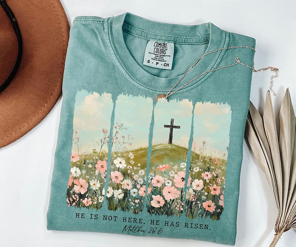 Teal t-shirt: cross, flowers, 'HE IS NOT HERE, HE HAS RISEN. MATT 28:6'.