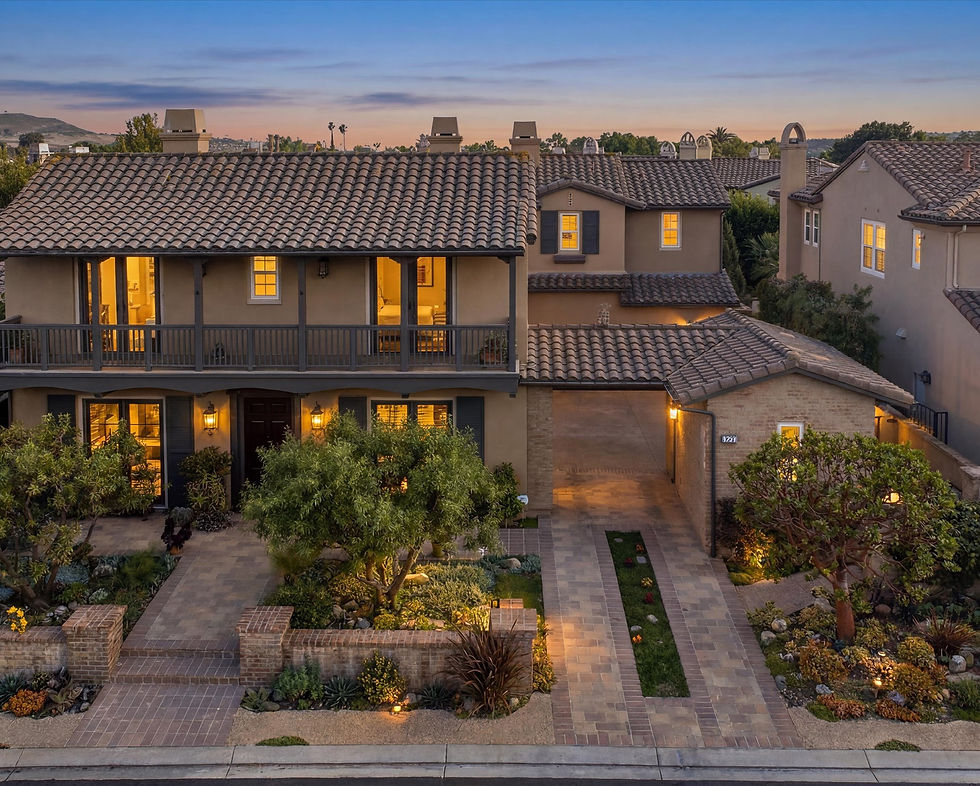 Twilight exterior view of the luxury Monterey Colonial estate at 31441 Paseo Caliz in Rancho Madrina, San Juan Capistrano, featuring a second-story balcony, clay tile roof, and a beautifully landscaped driveway.