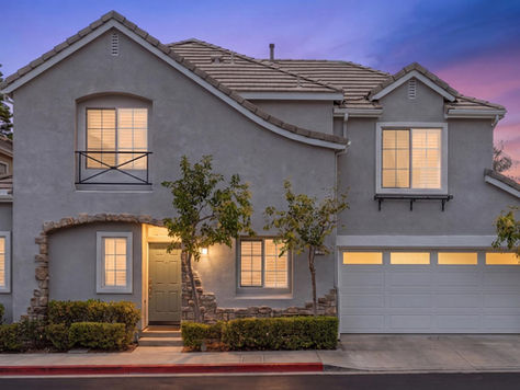 Front exterior view of 15 Poppyfield Lane, a two-story corner residence for sale in Las Flores, CA 92688, featuring stone-accented architecture, a covered front entry, an attached two-car garage, and classic window shutters.