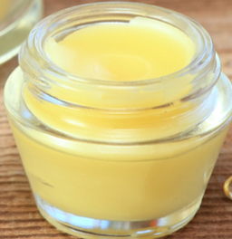 Close-up of yellow balm in a glass jar, J's Natural Soaps & More.