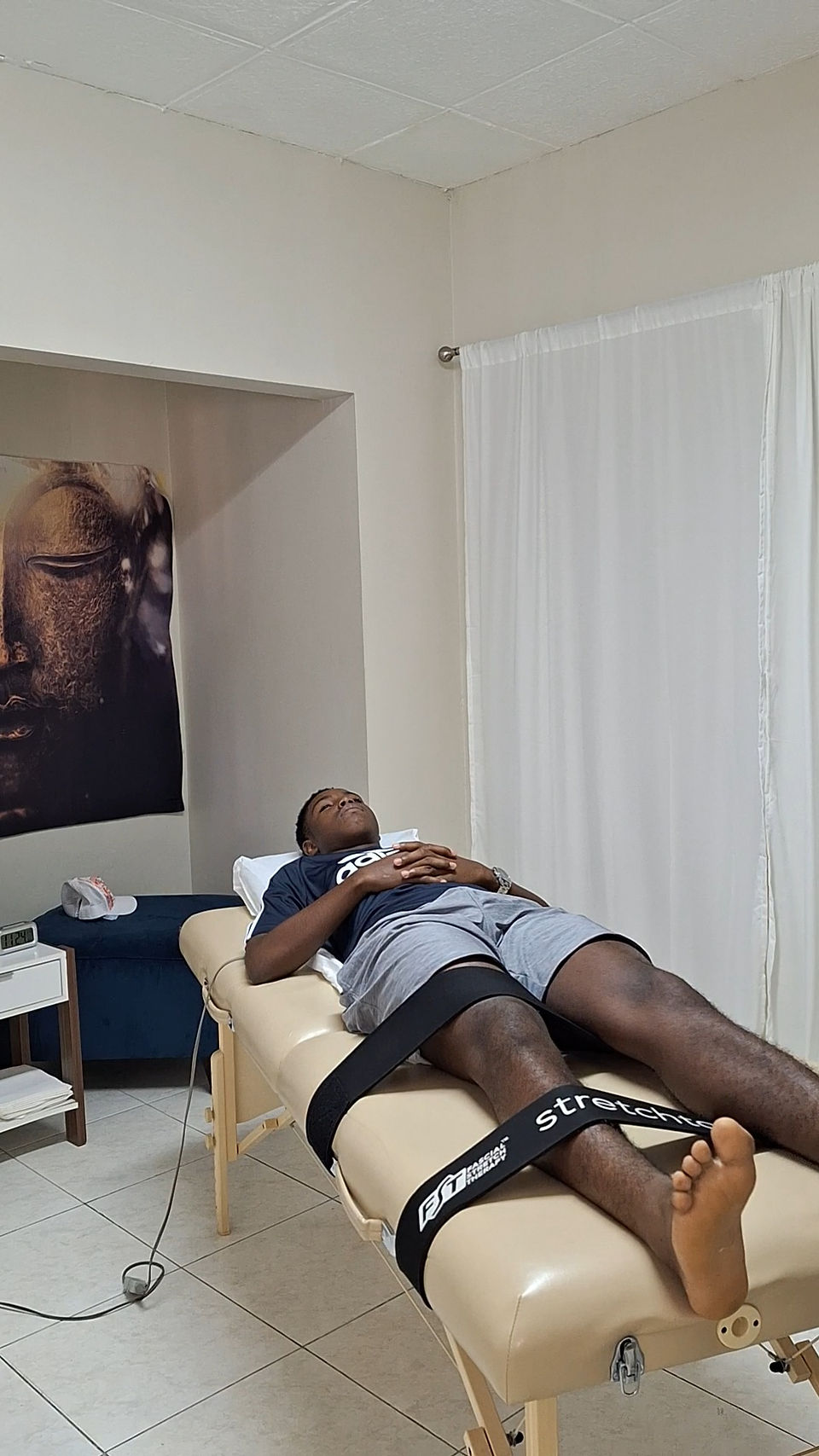 Male track and field athlete laying on a massage table awaiting fascia stretch session