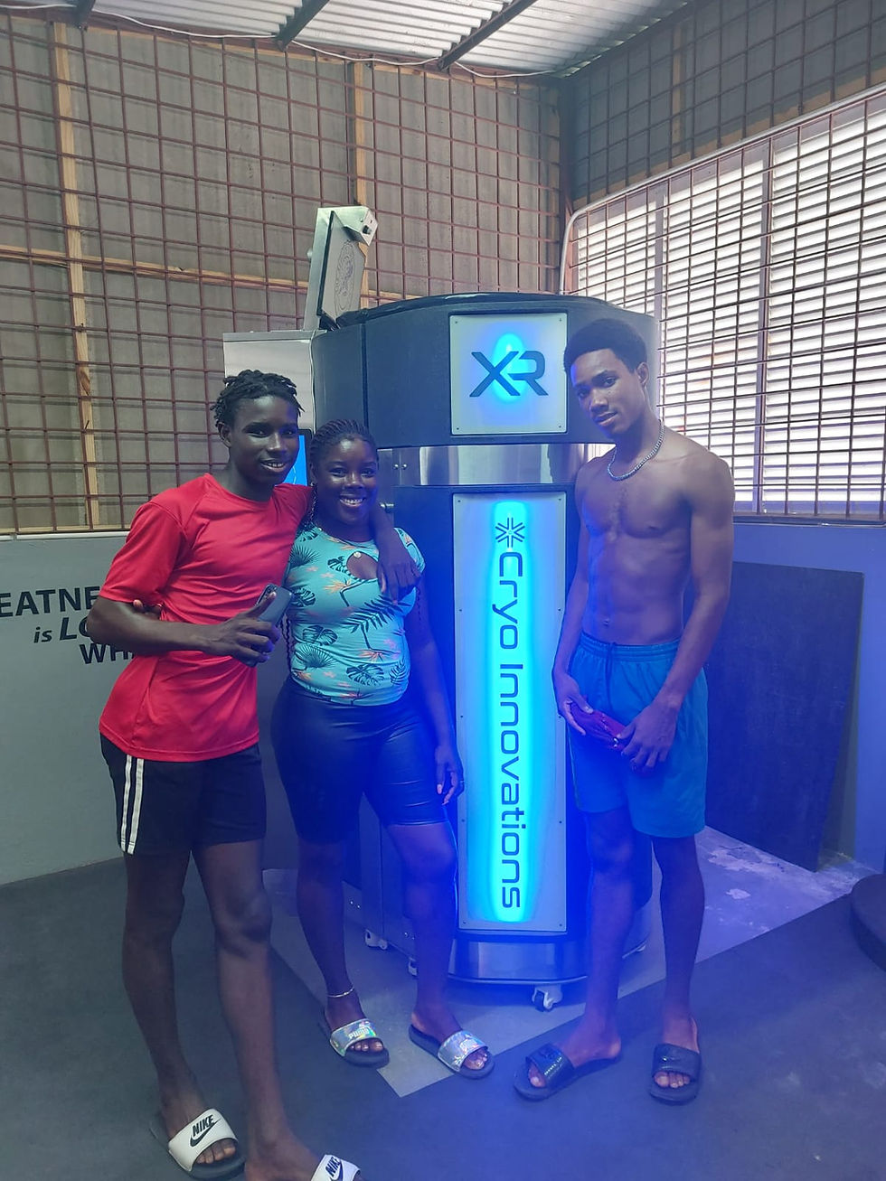two track and field athletes standing in front of the cryotherapy chamber with their mother