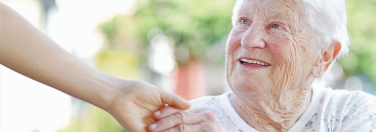 A smiling elderly woman shaking hands with a new companion.