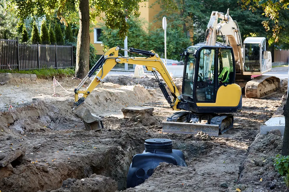 Mini-pelle creusant une tranchée en zone urbaine pour poser une cuve enterrée, exemple de terrassement soumis à l'art. 3 OSites sur un site pollué