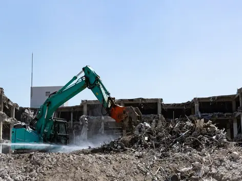 pelle mécanique qui démolie un batiment et qui dépose les déchets au centre