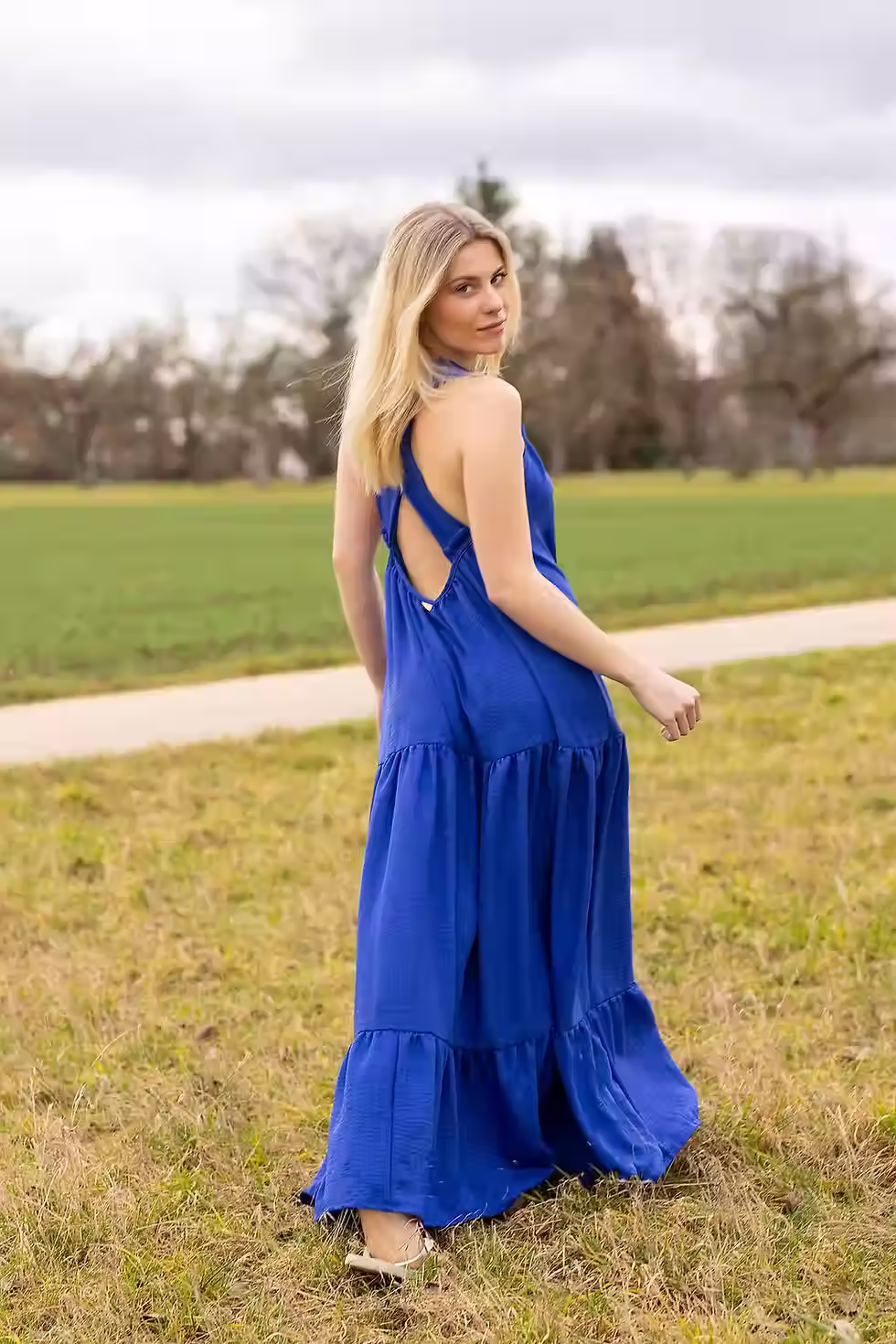 Elegante Frau in einem leuchtend blauen Maxikleid mit Rüschen und lockerem Schnitt, ideal für sommer-und herbstlich Anlässe