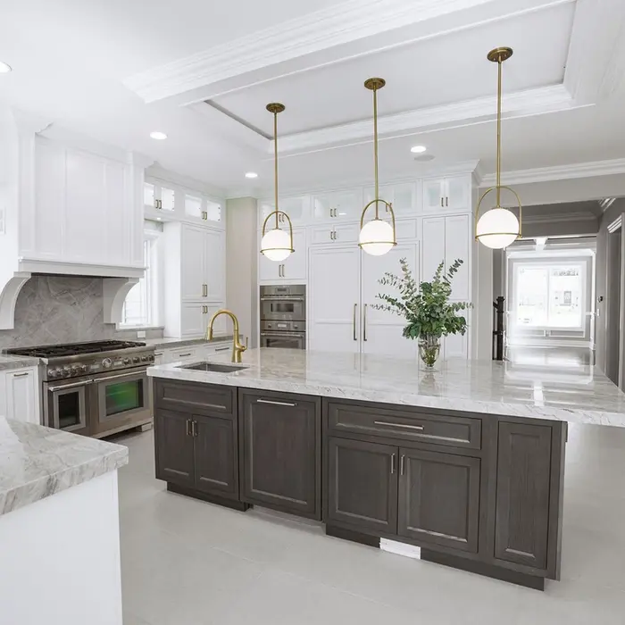 Bright, modern kitchen with large center island, white cabinetry, and gold pendant lighting