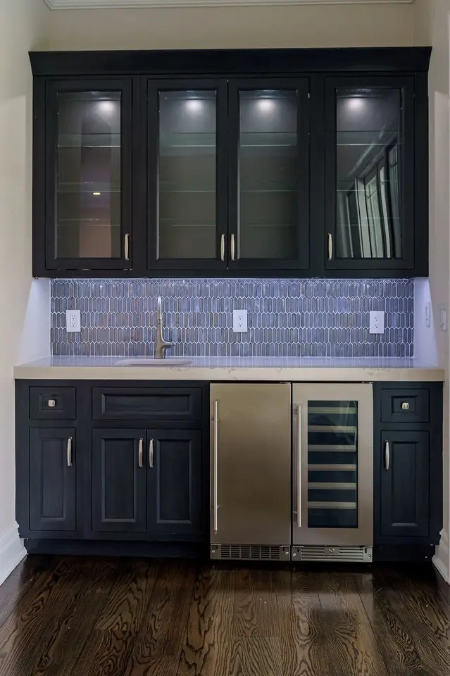 Built-in dark bar cabinets with glass uppers, under-cabinet lighting, and a beverage cooler
