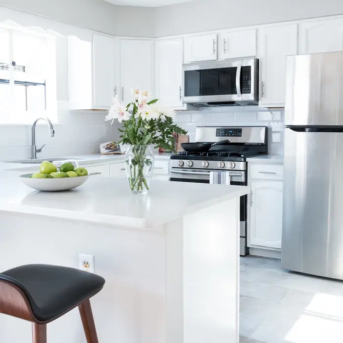 Bright white kitchen with stainless steel appliances and quartz countertops