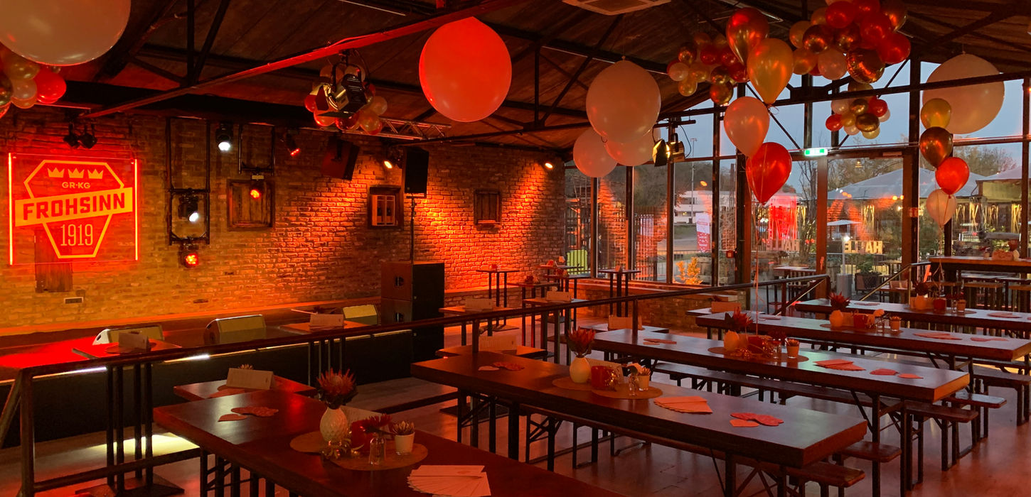 Industrielles Loft mit Backsteinwänden und Biergarnituren in festlicher Beleuchtung.