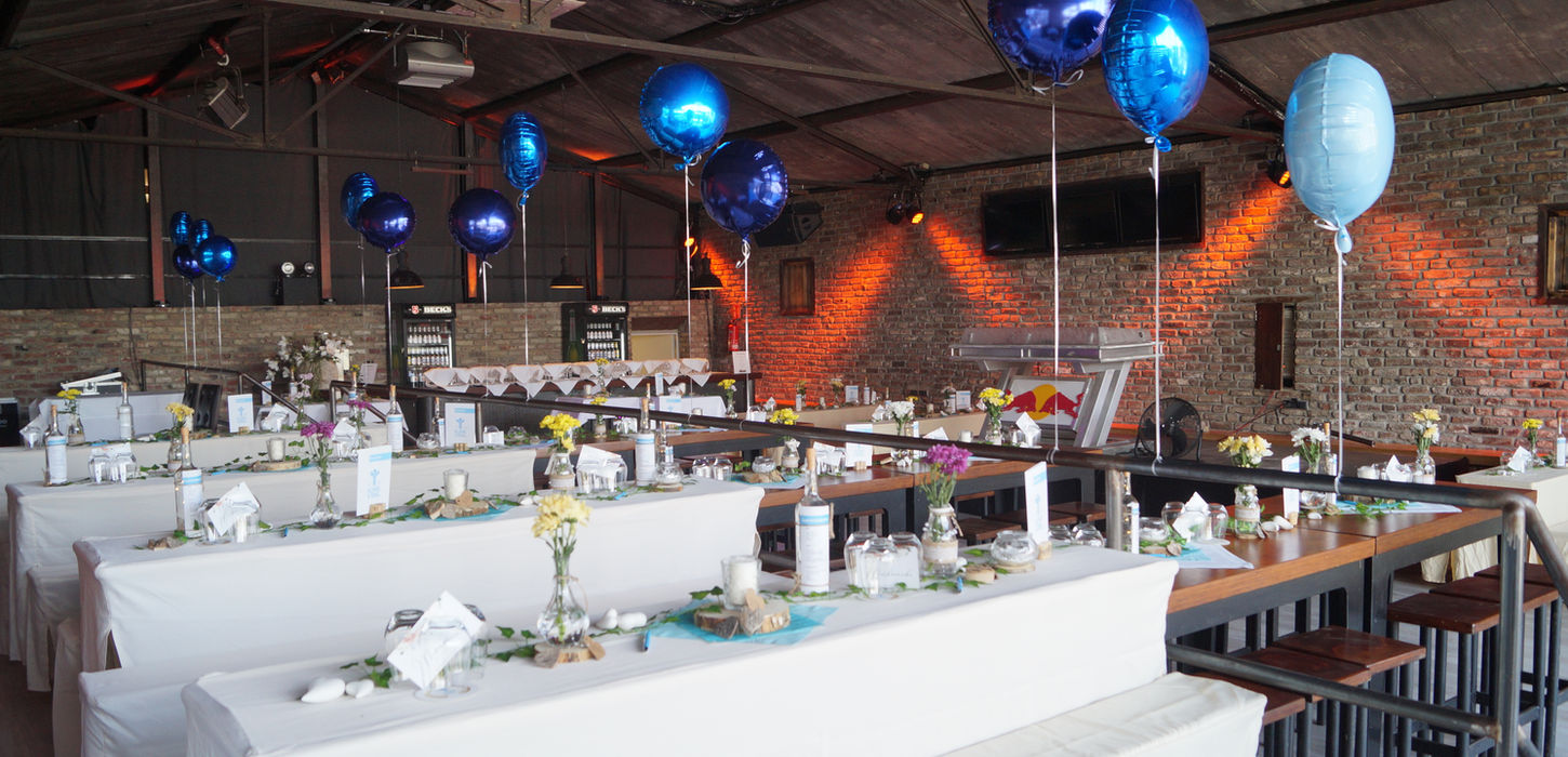 Industrielles Loft mit großen Fensterfronten, Backsteinwänden und Tischen und Ballondeko.