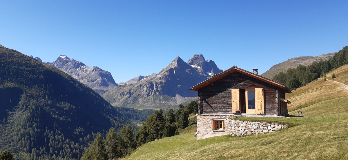 Una baita di montagna tradizionale con sfondo di vette alpine nel Parco Nazionale dello Stelvio.