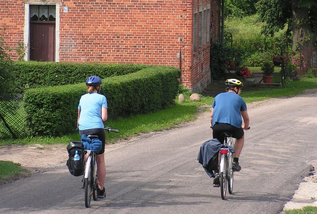  Due ciclisti indossano abbigliamento blu e caschi mentre pedalano lungo una strada di campagna.