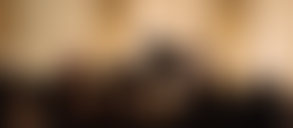 薄暗い空間で、ピアノと弦楽器の演奏が行われ、観客が静かに向き合って座っている。背景には淡い光の粒が壁面に広がり、キャンドルのような灯りがステージ周囲をやわらかく照らしている。