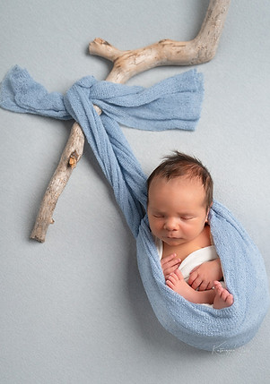 Nyfødt baby sovende i blå wrap, kreativ portrett med naturlige elementer under nyfødtfotografering hos KG Photography fotostudio i Sætre, nær Oslo, Asker og Drammen.