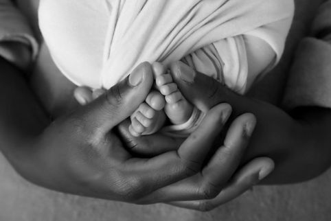 newborn feet in the hands of his fathers hands - the image is in black and white