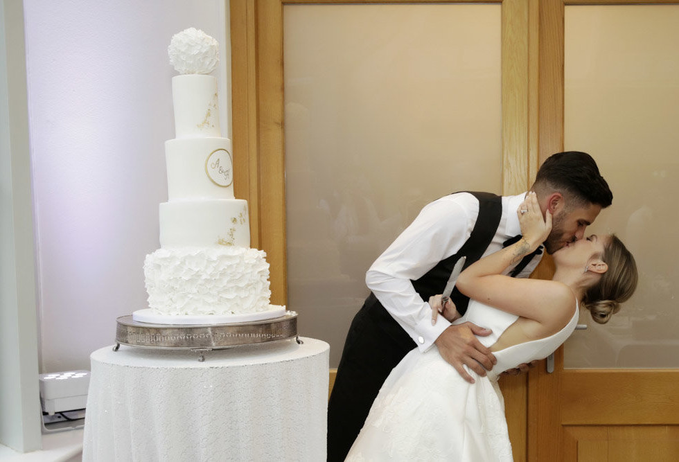 Botleys mansion wedding bride and groom kissing after cutting the cake