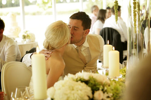 Bride and Groom stealing a kiss during their Surrey Marquee wedding breakfast