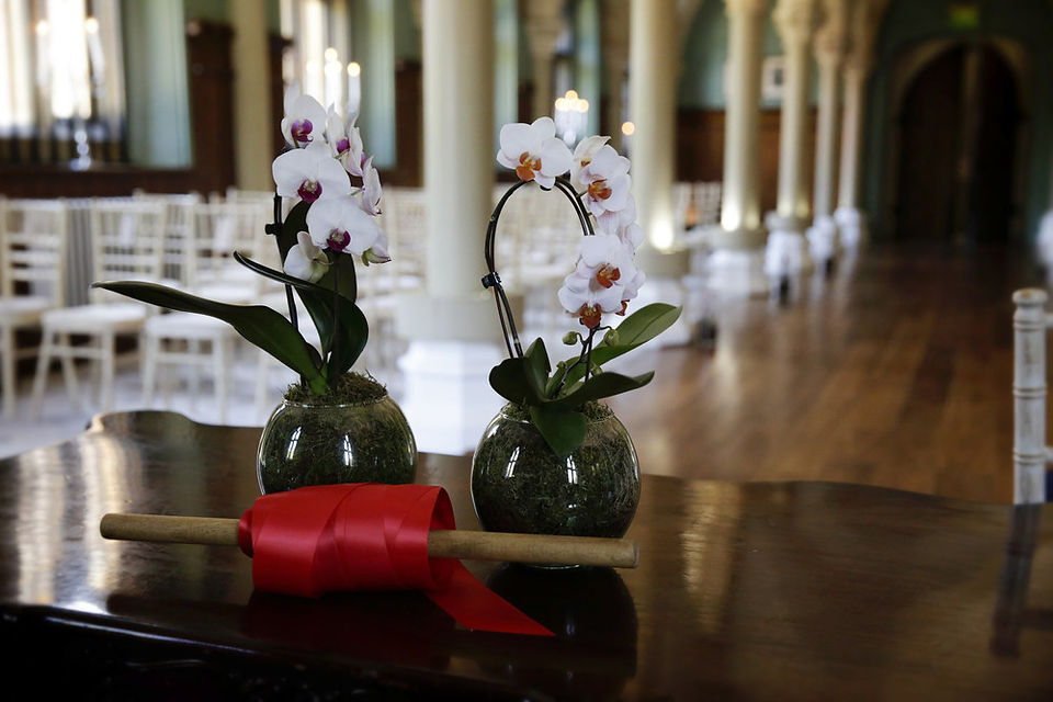 Wotton House Wedding orchids and red ribbon on table in pillared library before humanist ceremony
