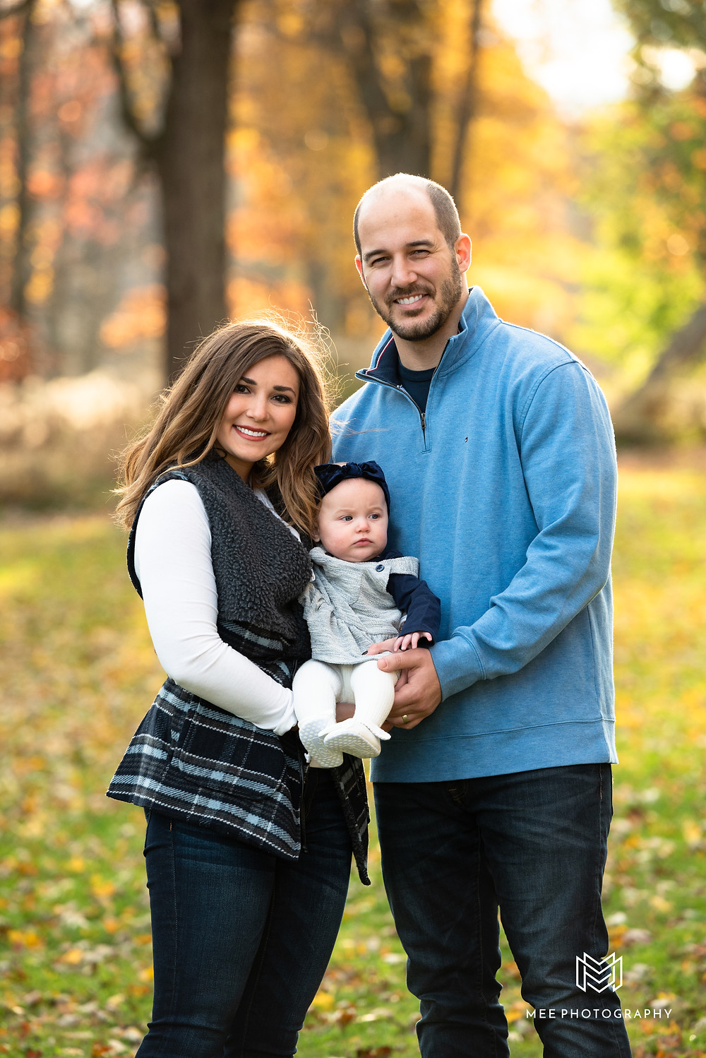 Fall photos with a five month old baby and her parents posed smiling at the camera