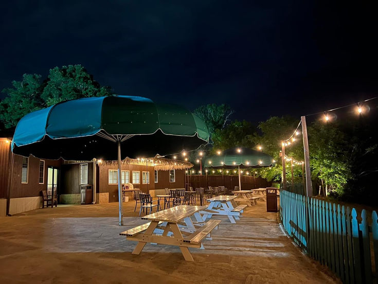 Pool deck with green umbrellas and string lights at night