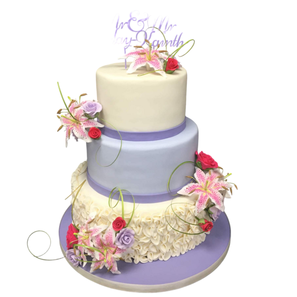 Three-tiered wedding cake with sugar paste, lilies, roses, and textured ruffles.