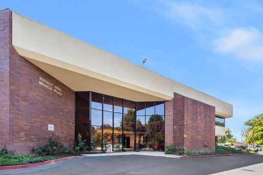 Exterior view of Project Sister Family Services’ new office at Royalty Drive Medical Plaza, featuring large glass windows and a brick facade.