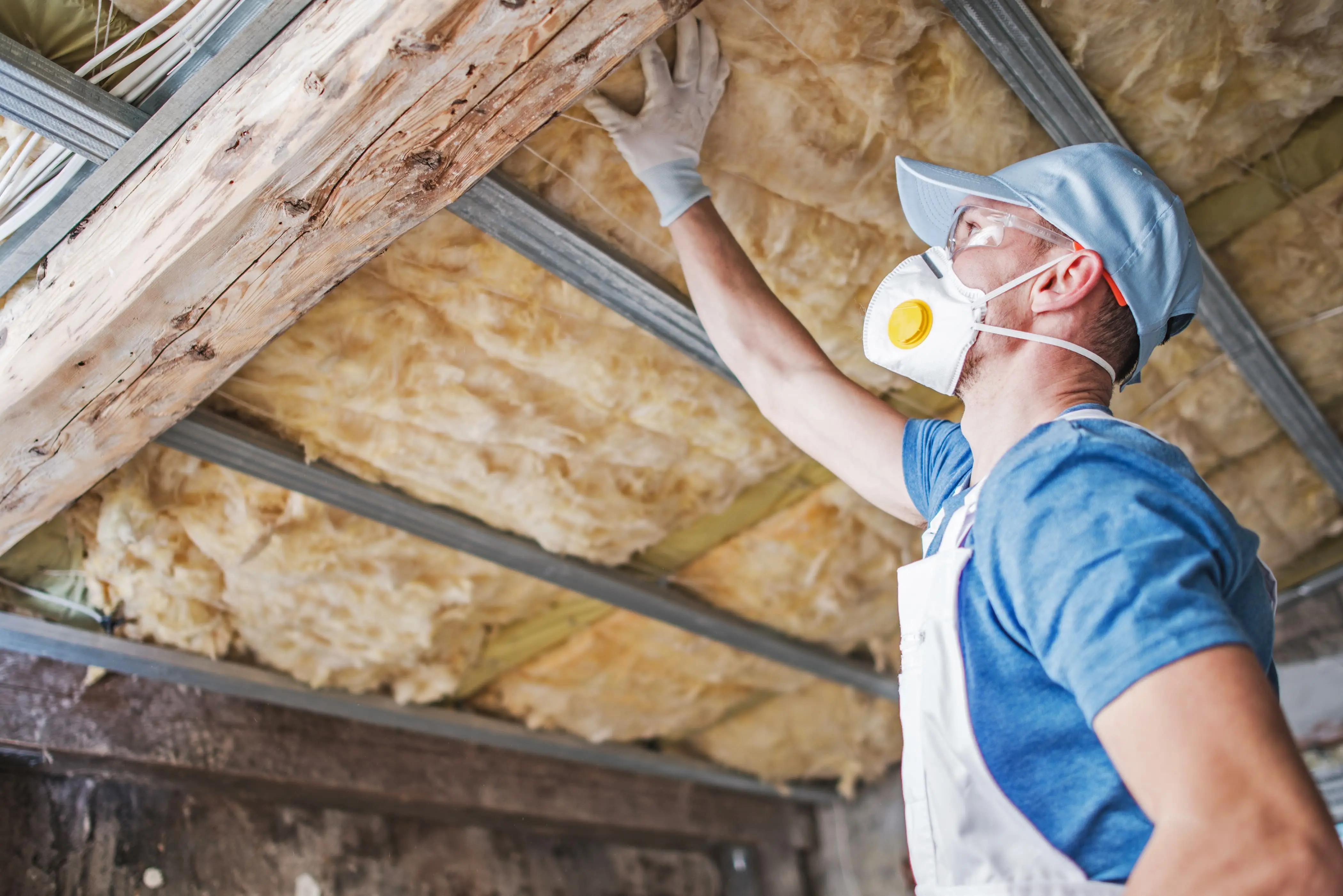 Pest control worker inspecting existing insulation in an attic