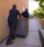 HVAC technicians moving an old AC unit our of a home so that they can replace it with a new unit