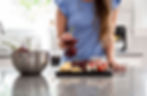 young woman at kitchen counter placing grapes on charcuterie board