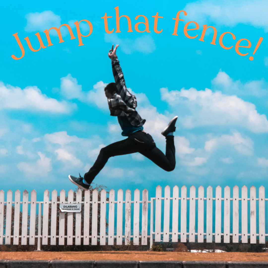 A person jumps over a white picket fence