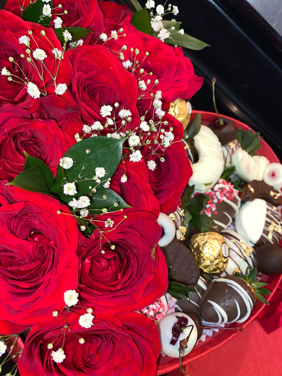 Luxury floral arrangement with chocolate covered strawberries in a premium gift box.