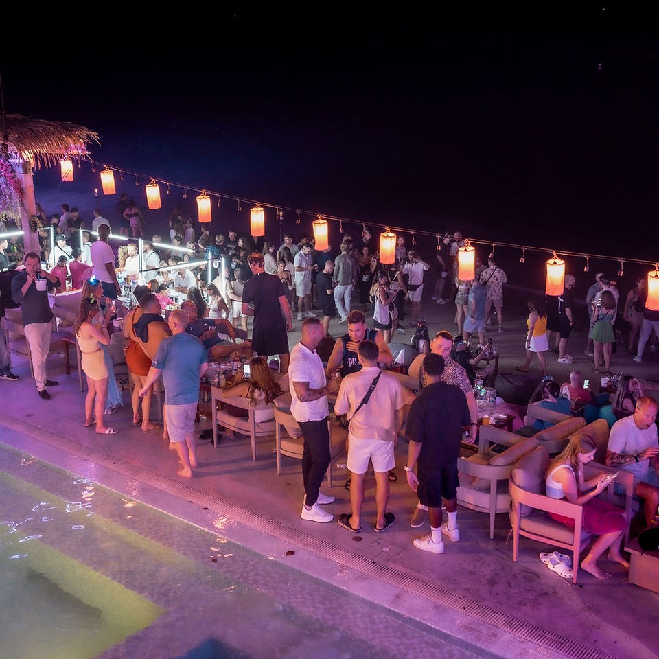 Couches beside the pool and lanterns along the beach at Love Beach Club on New Year's Eve 2025