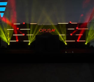 Event stage with red and yellow lighting, 'OPUS' sign