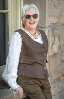 She is wearing a blousy white shirt and brown vest and pants to imitate a Steam Punk style.