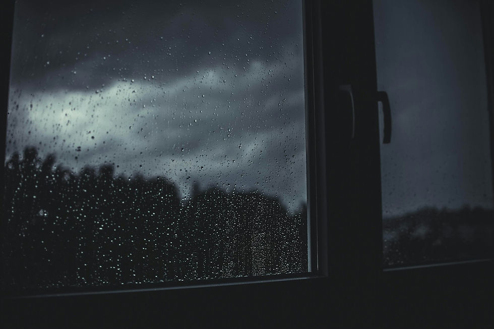 Janela com gotas de chuva e céu cinzento