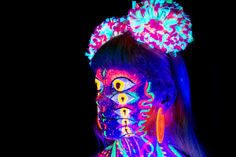 Neon body paint with glowing accessories in UV light with lots of eyes.