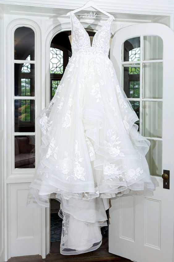 White lace wedding dress hanging in a doorway.