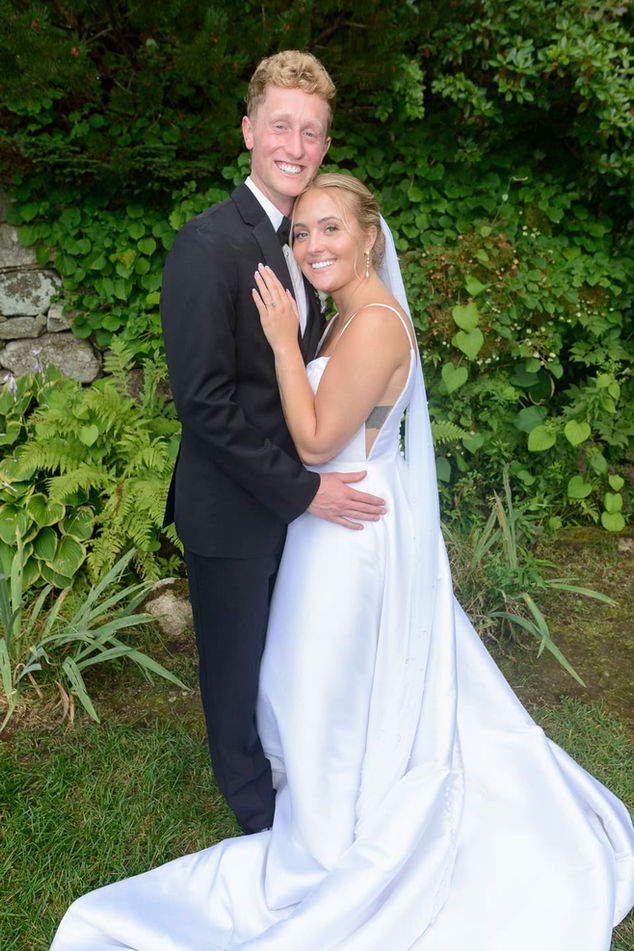 Bride and groom full-length portrait smiling in garden.