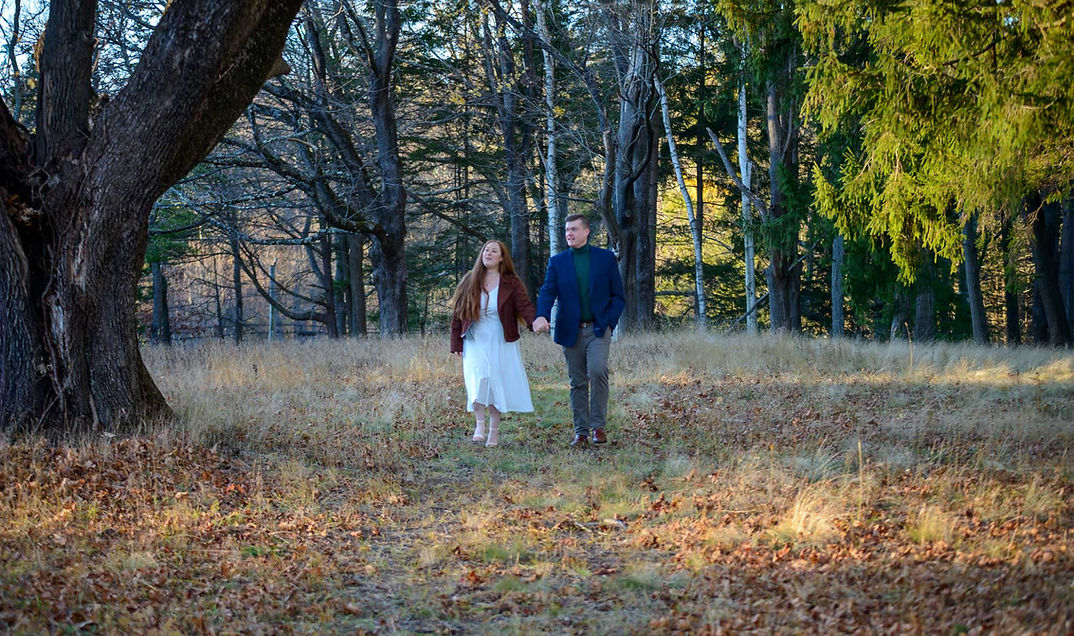 Romantic couple walking through meadow at Maudslay State Park in Newburyport Massachusetts during engagement session
